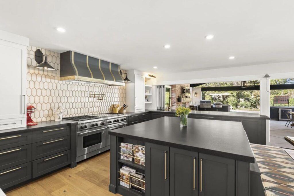 Modern kitchen featuring sleek dark cabinetry, a spacious island, and a stylish hexagonal backsplash. Natural light highlights the open layout, ideal for entertaining.