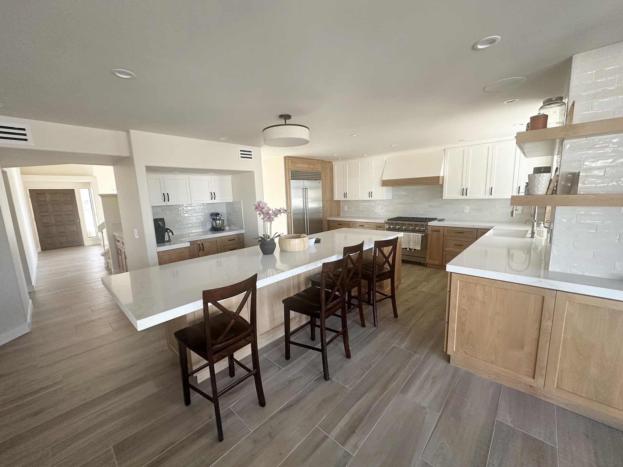 Modern kitchen featuring wooden cabinets, a large island with seating, and stainless steel appliances. Bright and spacious, ideal for cooking and entertaining.